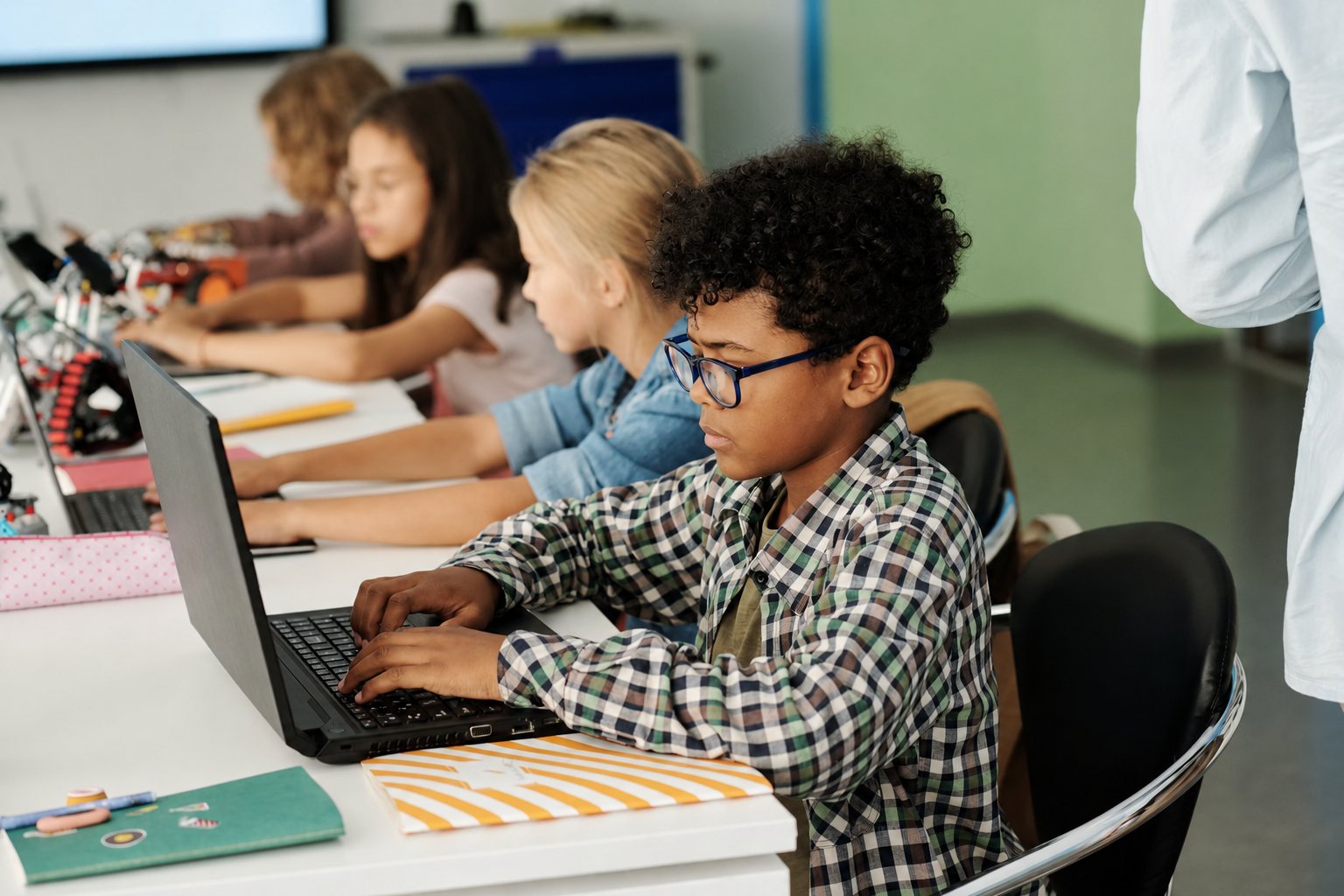 Leerlingen werken geconcentreerd achter hun laptops in de klas.