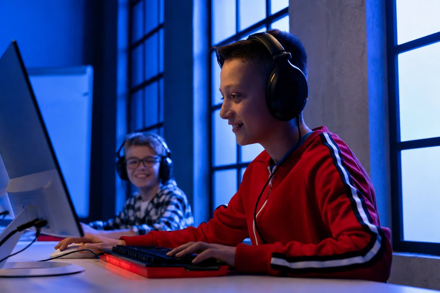 Twee leerlingen met koptelefoons bouwen samen aan een game achter de computer.